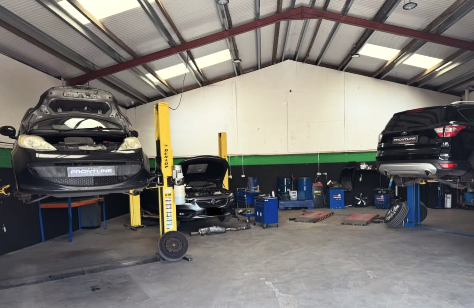 Inside the Frontline Autocare workshop with vehicles up on the ramps